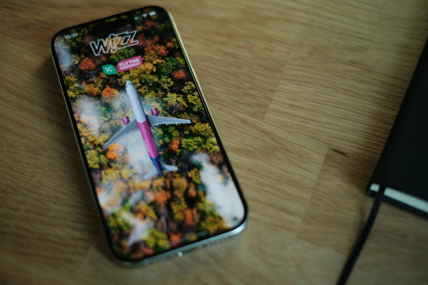 Smartphone con app di prenotazione voli su una scrivania di legno.
