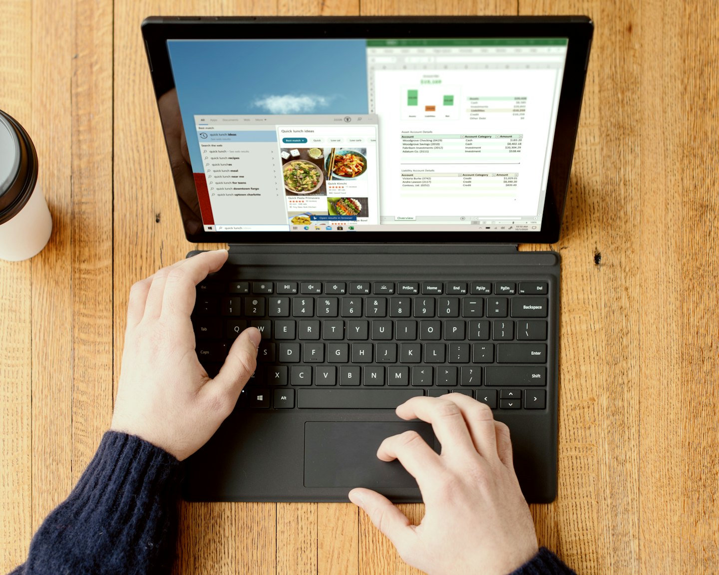 Mani che digitano su un laptop che mostra dati e risultati di ricerca.